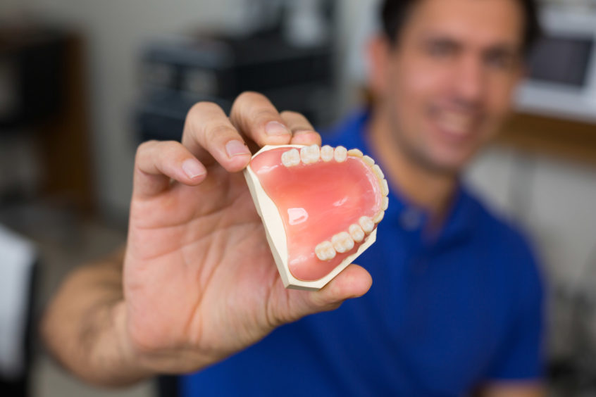 Dentist holding dentures partial